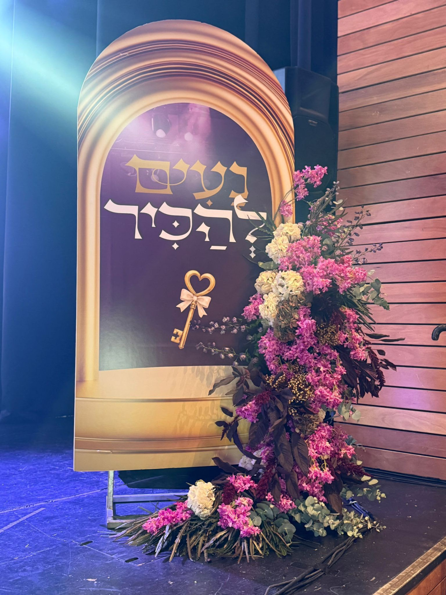 עיצוב במה בדמות שער מוזהב עם סידור פרחים